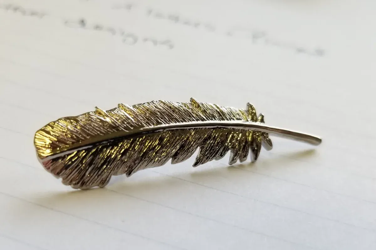 Finished custom 3D cast lapel pin shaped like a feather in polished silver finish