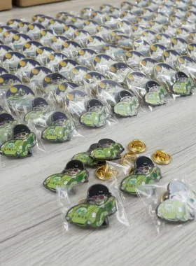 Tray of custom green vintage car lapel pins individually bagged for tradeshow giveaway