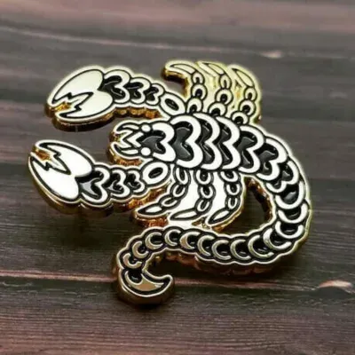 Custom die-struck lapel pin in antique gold with detailed scorpion design