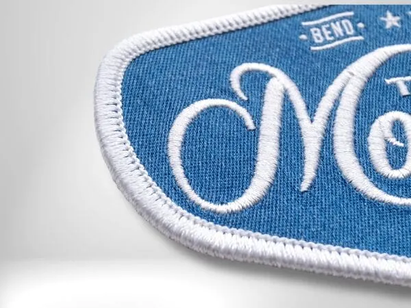 Blue embroidered patch with a white merrowed stitched border