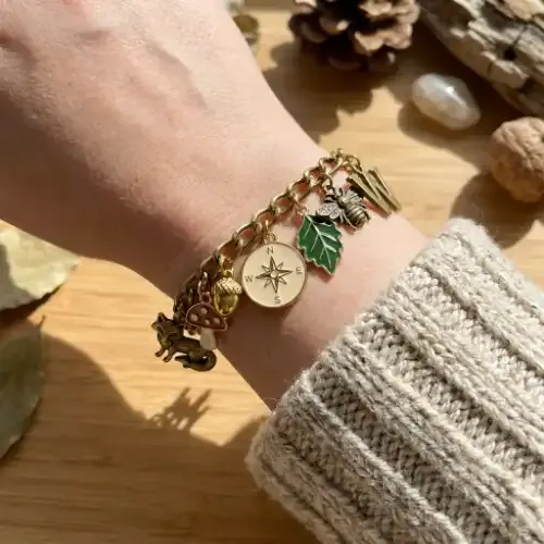 Finished custom charm bracelet worn on a wrist, featuring a mix of enamel and metal charms in a consistent color palette