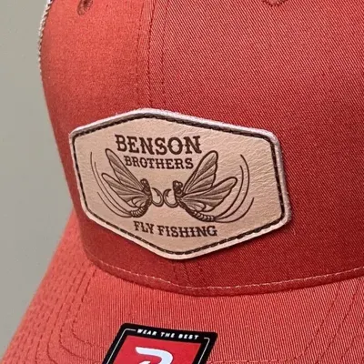 Leather fly fishing patch on orange hat