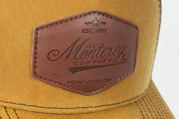 Custom leather Monterey Company patch on a tan trucker hat