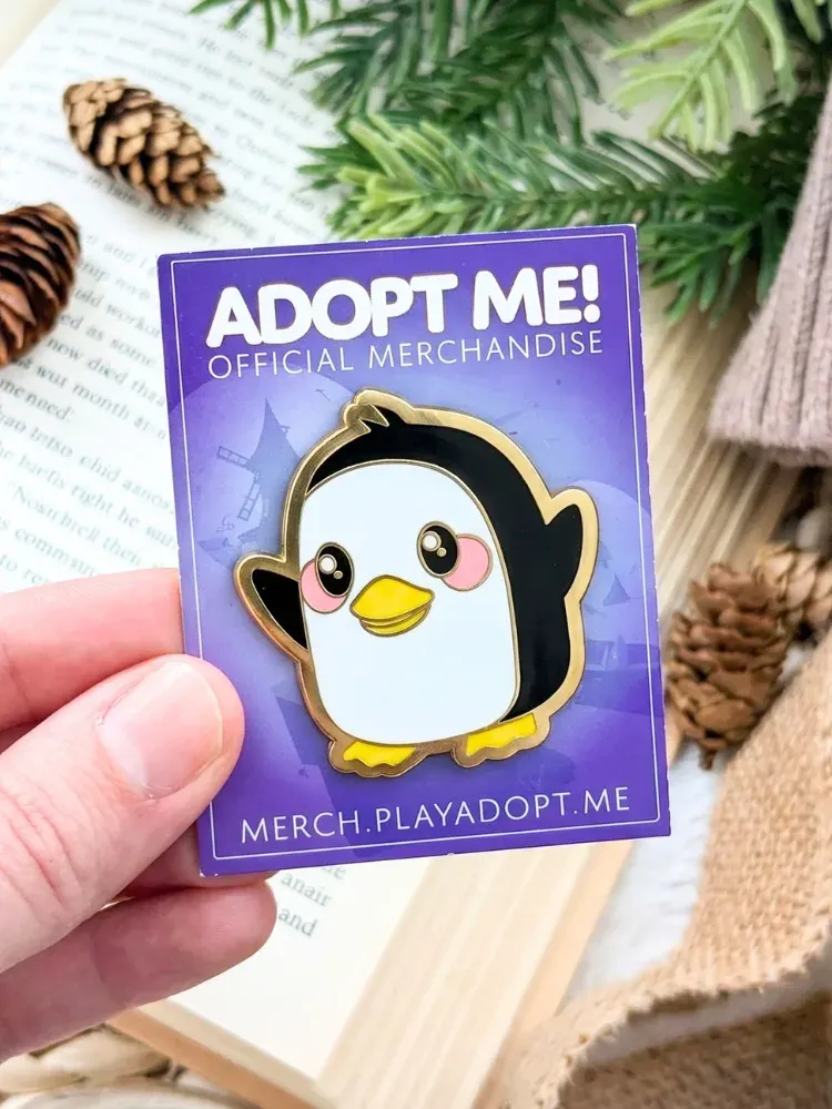 Custom penguin enamel pin mounted on a printed backer card