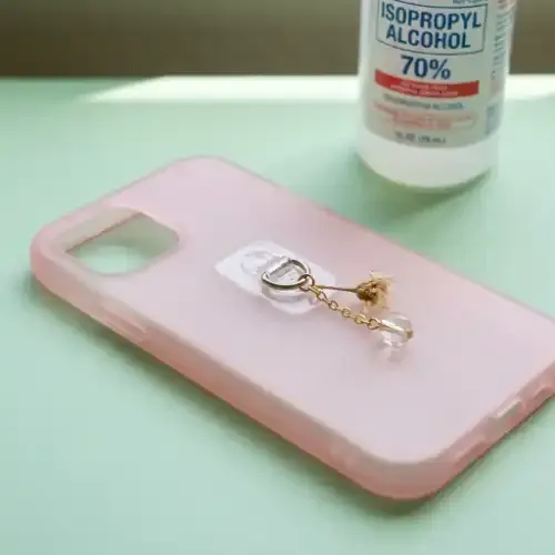 Adhesive charm tab on the back of a hard plastic phone case with a lightweight charm
