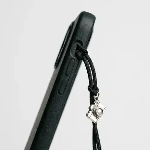 Attachment cord routed through a phone case mute switch cutout with a charm
