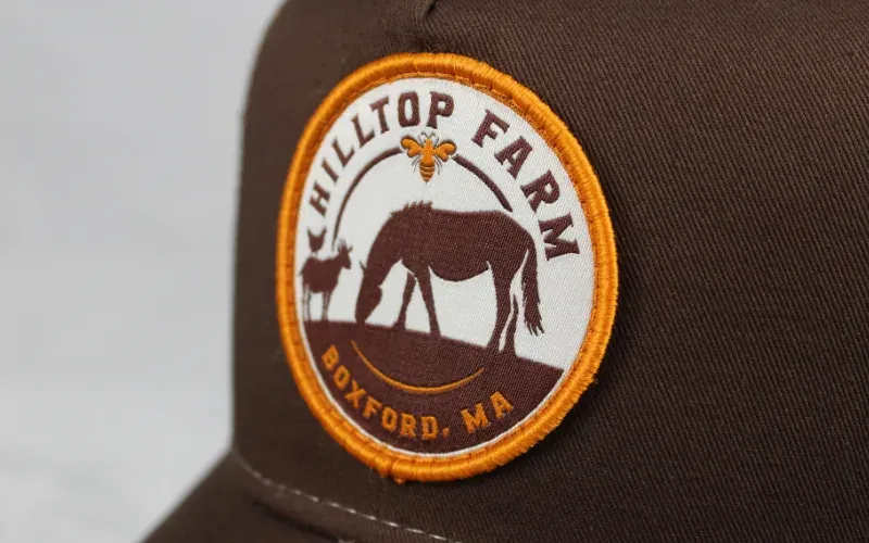Custom woven Hilltop Farm patch with a grazing horse on a brown trucker hat