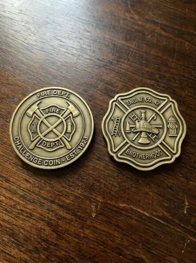 Round challenge coin next to a custom shield-shaped challenge coin